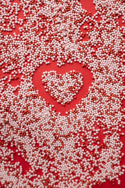 Free Top view of heart shape in scatter sprinkling on red background for Valentine day Stock Photo