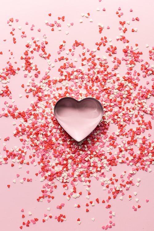 Paper confetti in heart shape on pink table · Free Stock Photo