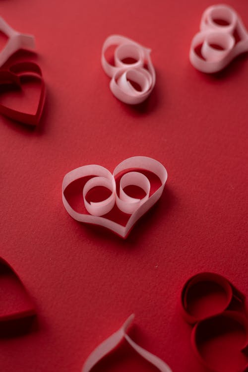 Paper hearts scattered on red surface