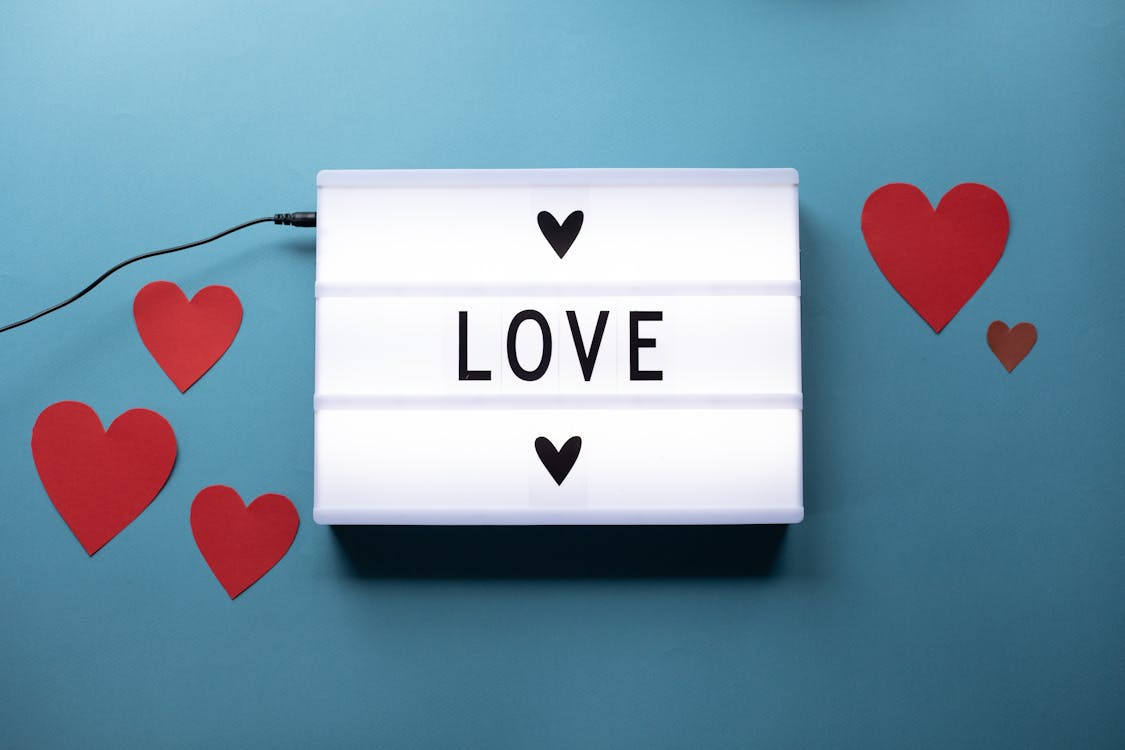 Composition of light box with Love word and glued paper hearts for Saint Valentine concept