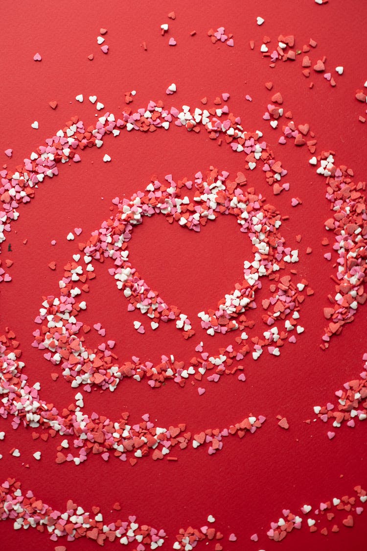 Confectionery Heart Shaped Sprinkles On Red Background