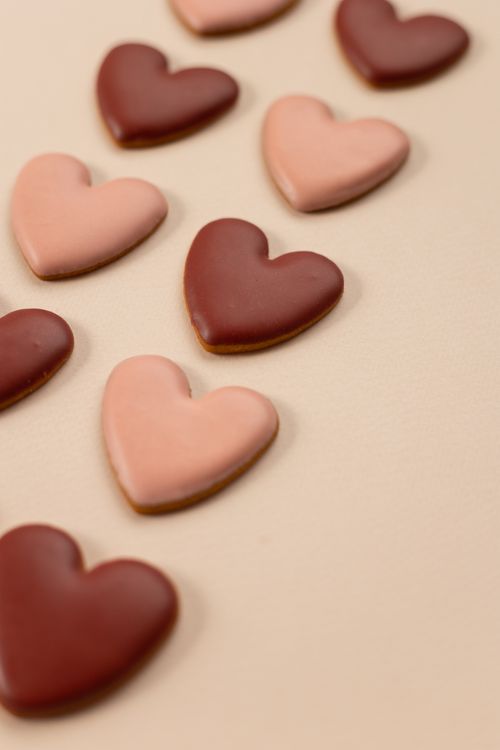 Free From above composition of red and pink heart shaped cookies with glaze arranged in rows on beige background on holiday day Stock Photo