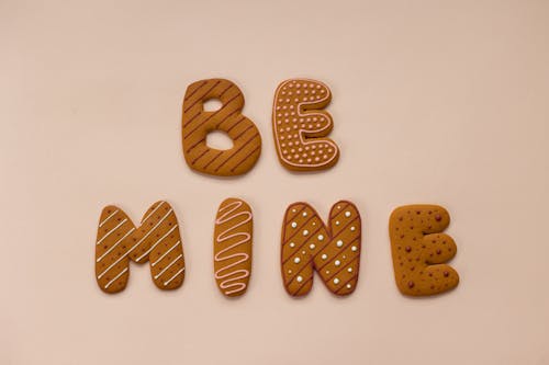 Free Top view of delicious cookies forming Be Mine phrase placed on beige background during celebration of romantic Saint Valentine Day Stock Photo