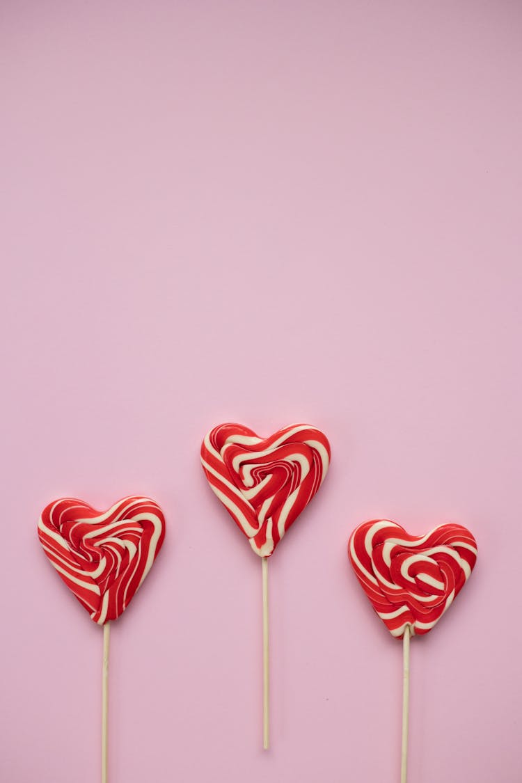 Sweet Lollipops In Form Of Hearts Against Pink Background