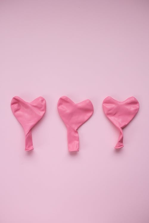 Pink balloons in form of heart against pink background