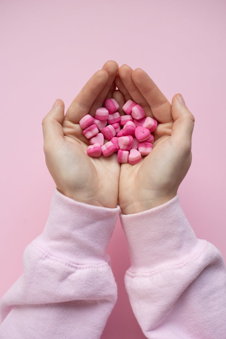 Person Showing Small Candies In Shape Of Hearts In Hands