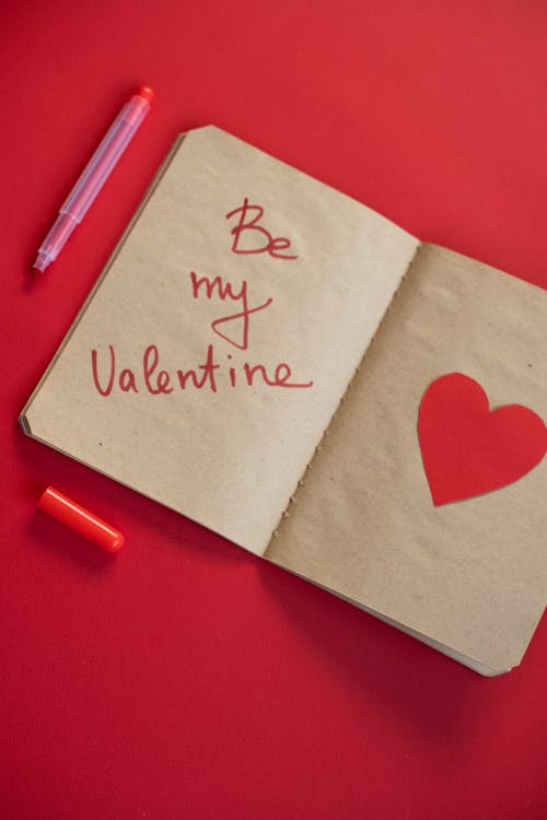 Top view of opened notebook with heart and words near marker in studio