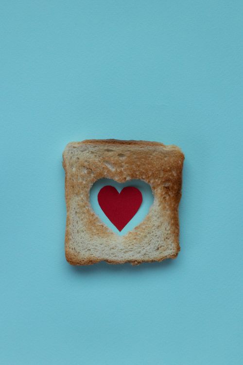 Free From above of piece of white bread with red paper heart on blue background Stock Photo