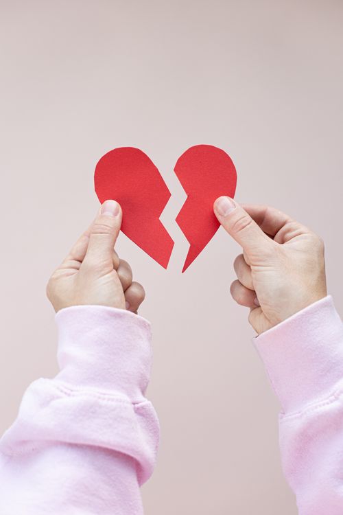 Free Crop anonymous person showing parts of red broken heart against white background in studio Stock Photo
