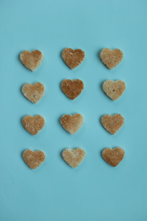 Free From above of crusty edible hearts from white bread on bright blue background Stock Photo