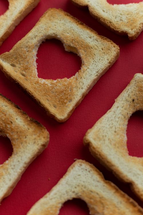 Free High angle of crispy toast bread with cut hearts on bright red background Stock Photo
