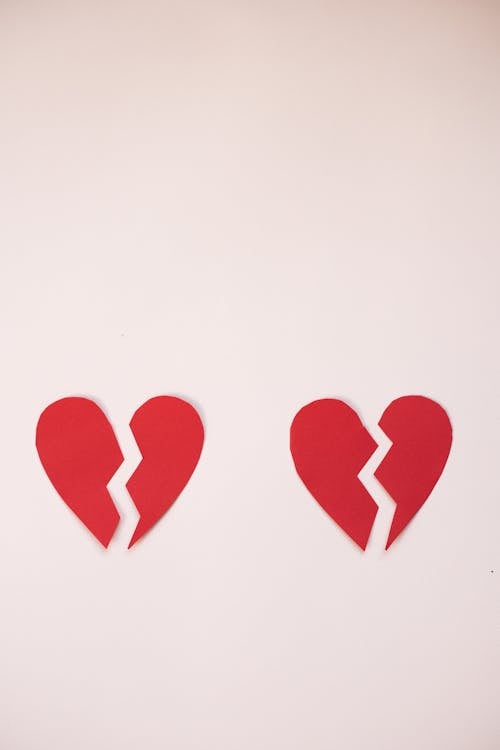 From above of cut parts of red broken hearts on light white background