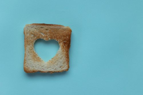 Free Top view of piece of white bread with cut heart on blue background Stock Photo