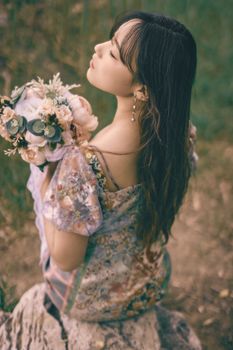 在北京的户外，一位优雅的女人闭着眼睛，手捧花束