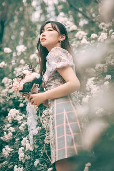 一位时尚的年轻女子在花园盛开的鲜花中优雅地摆弄花束