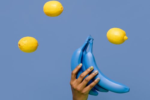 Free A creative and vibrant image featuring blue bananas and floating lemons against a solid background. Stock Photo