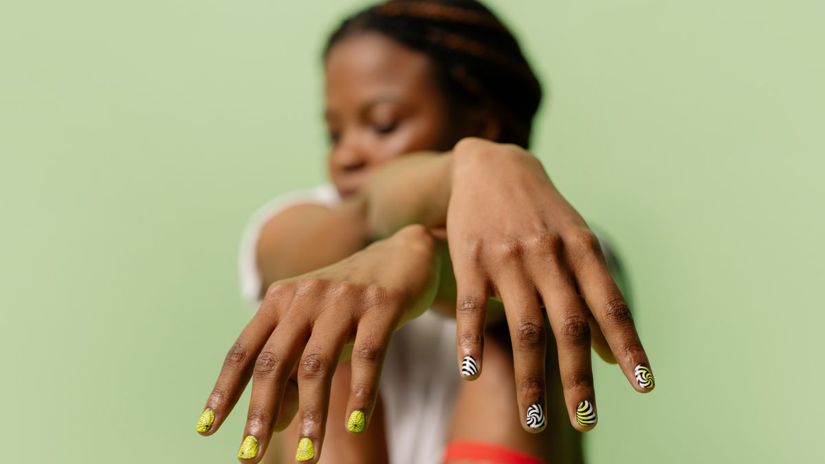 simple nail designs at home shown on a hand with colorful manicure against a green background
