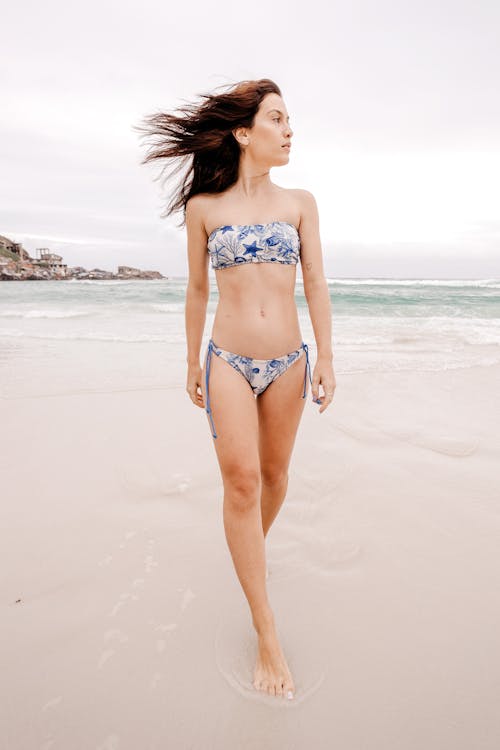 Free Slim female model in swimwear walking on sea coast Stock Photo