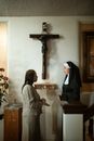 在教堂里，一个修女和一个女人在十字架下讨论信仰