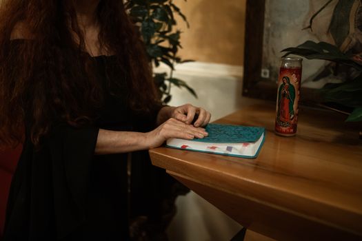 一个女人在室内的木桌旁，借着宗教蜡烛的光阅读圣经，营造出一种精神氛围