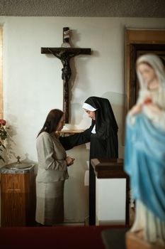 教堂里，一位修女和一位女子在祈祷中交谈，描绘了精神联系