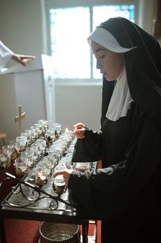 在优雅的小教堂内，一位沉思的修女点燃蜡烛，散发着宁静和奉献精神