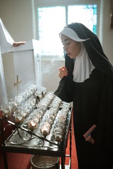 在教堂里，一位修女点燃蜡烛，体现了奉献和灵性