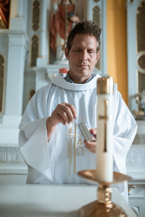 Free A Priest Lighting a Candle Stock Photo