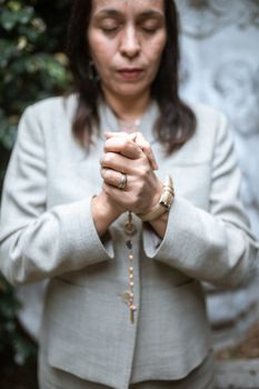 一个女人在户外用念珠祈祷的特写，展现了信仰与灵性