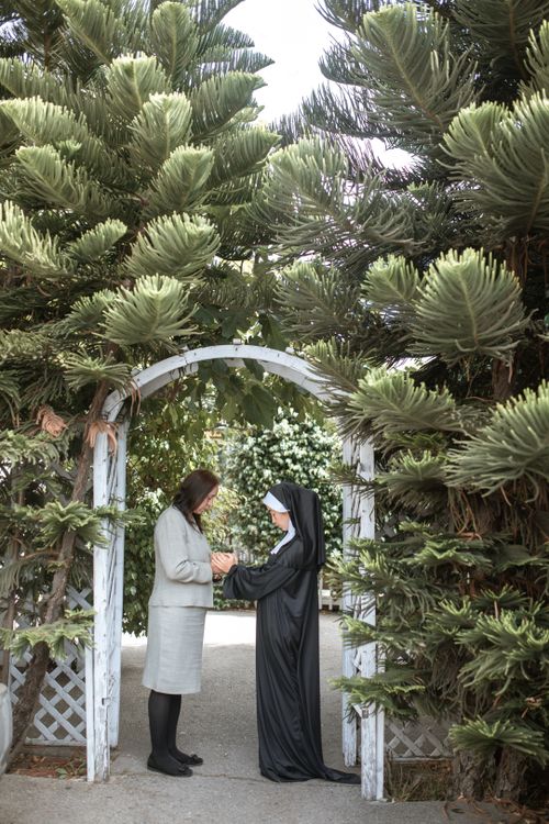 Free A nun and woman stand beneath a garden arch, praying outdoors. Stock Photo
