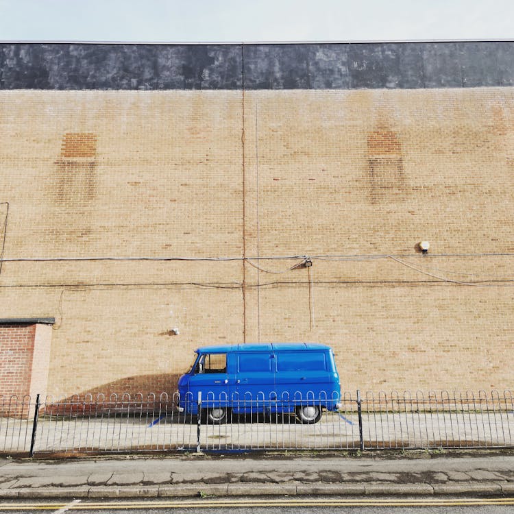 Old Blue Bus Parked On The Side Of A Building 