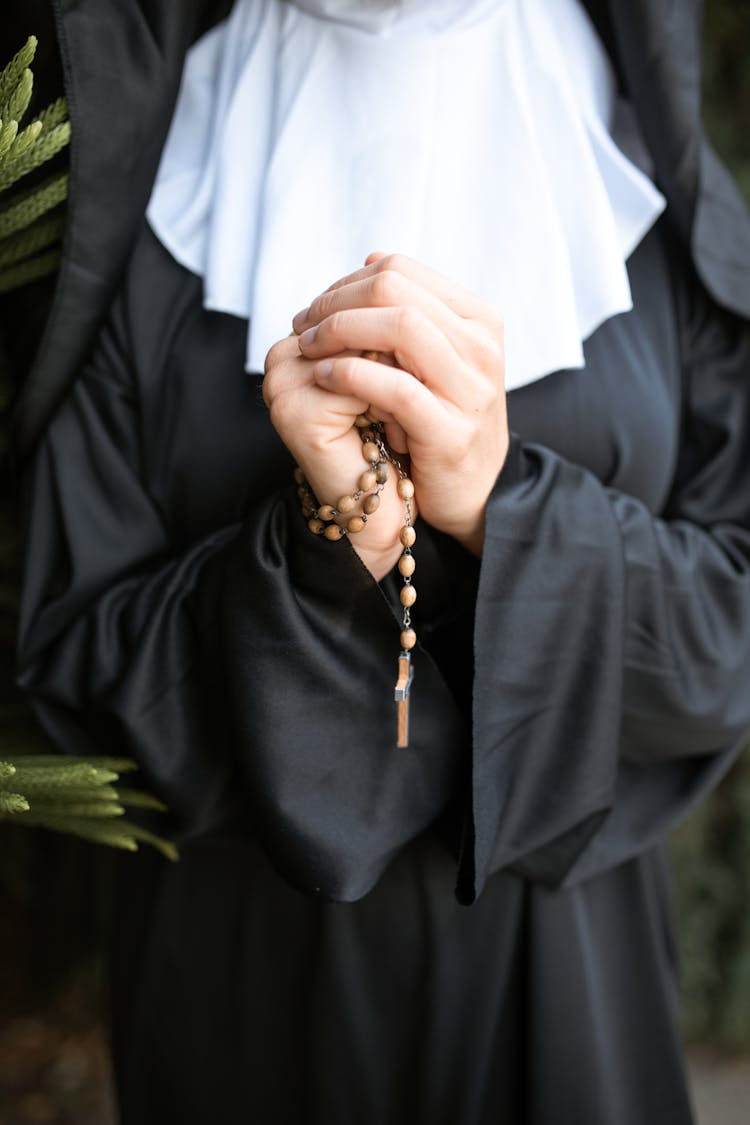 A Nun Using A Rosary While Praying