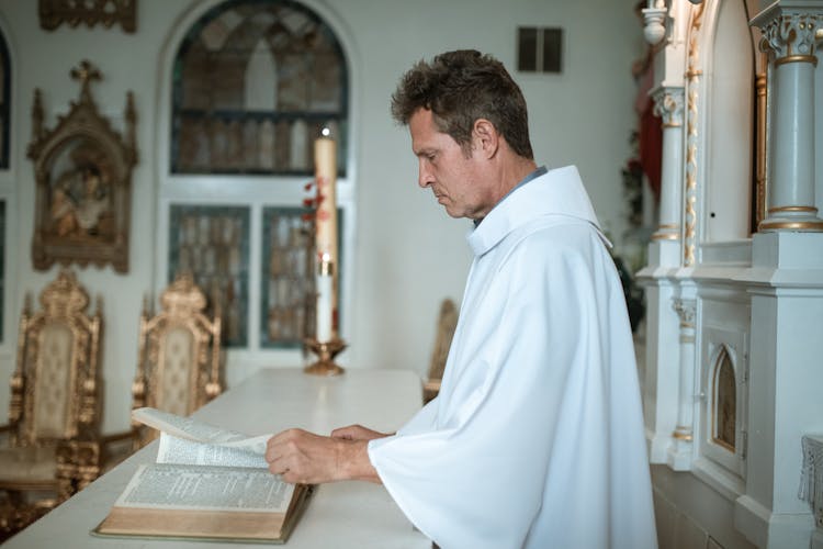 Priest Turning Pages Of Book On Altar 