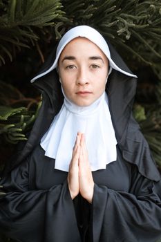 一位身着传统服装的成年修女，在户外安详地双手紧握祈祷