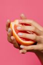 Person Holding Orange Fruit With Pink Background
