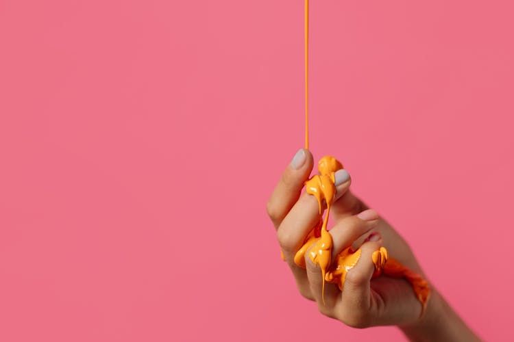 Orange Paint Dripping On A Person's Hand