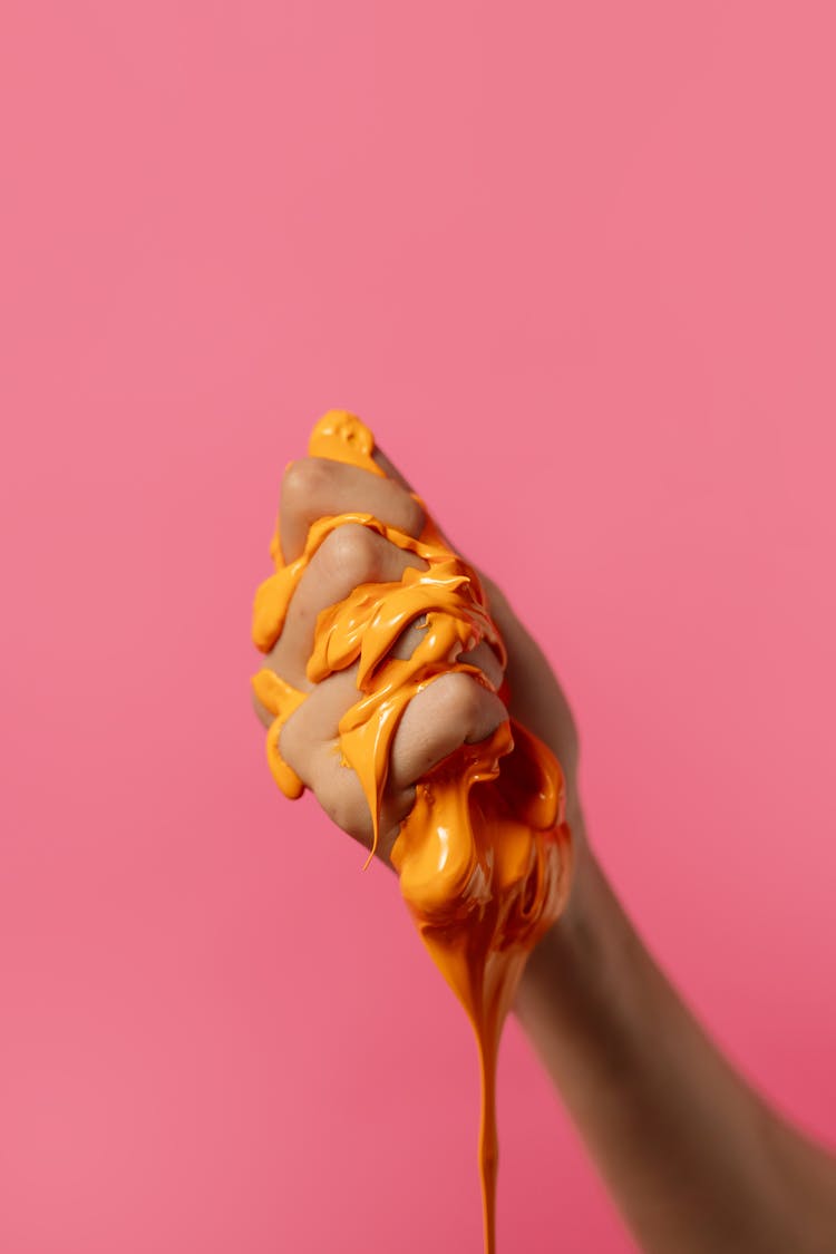 Person Squeezing Orange Liquid