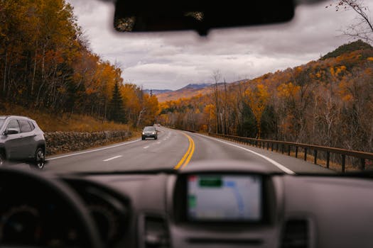 Driving on a scenic fall road, surrounded by colorful trees and mountains.