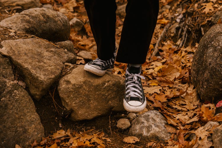 Anonymous Person In Sneakers Walking On Stones