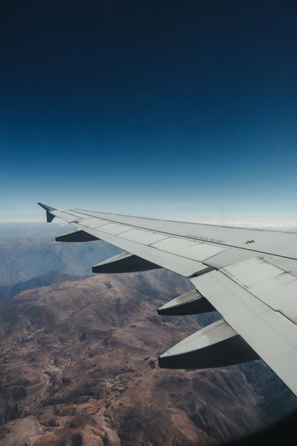 Captivating aerial view from airplane window showcasing expansive mountain range under clear sky.