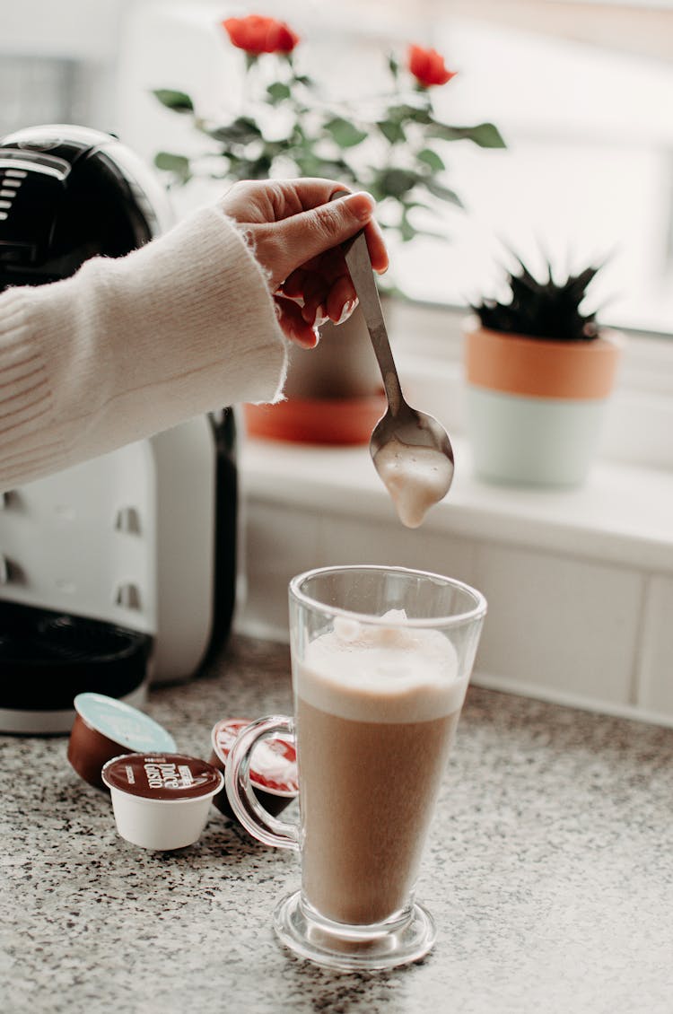 Woman Preparing A Latte At Home From A Capsule Espresso Machine 