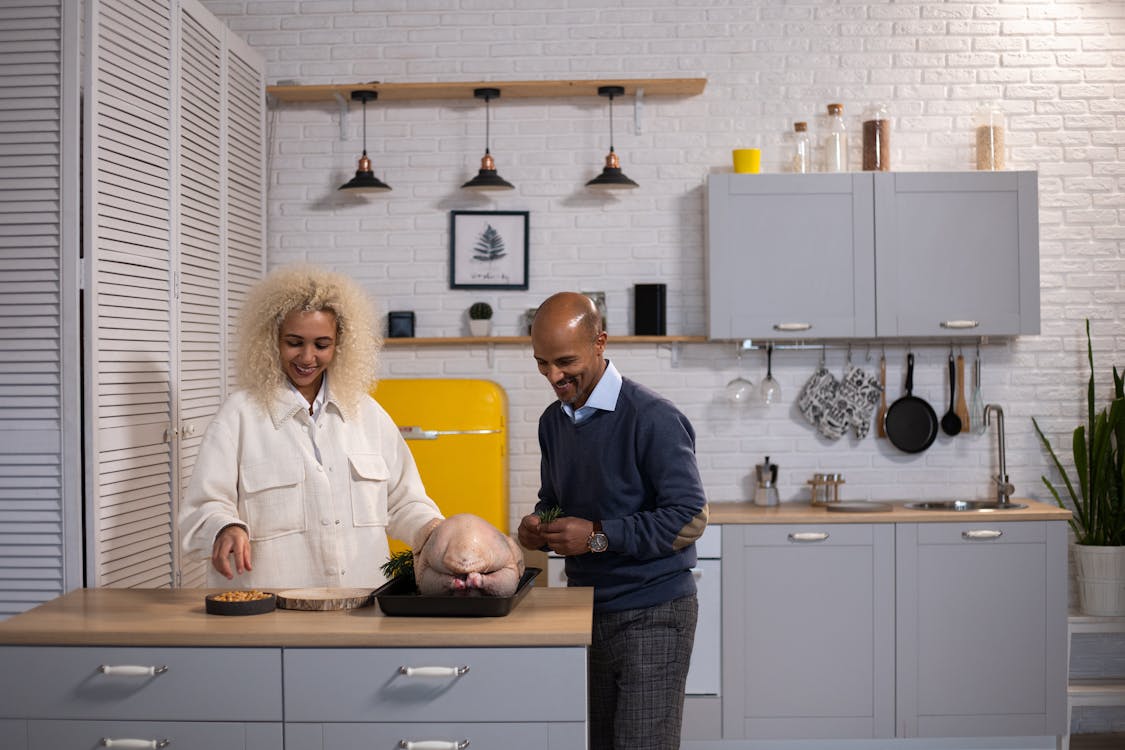 Positive black couple preparing turkey in kitchen