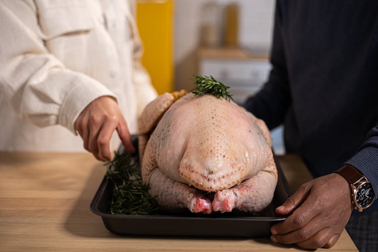 Crop Black Couple With Raw Turkey On Table