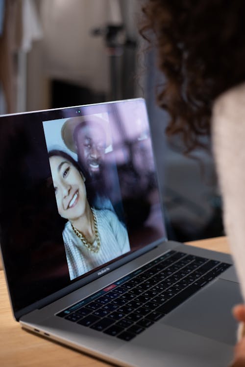 Crop woman making video call on laptop