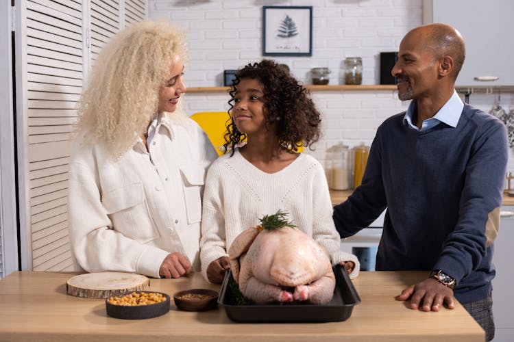 Black Family Cooking Turkey In Kitchen