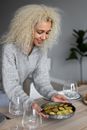 Cheerful black woman putting bowl of delicious meal on table