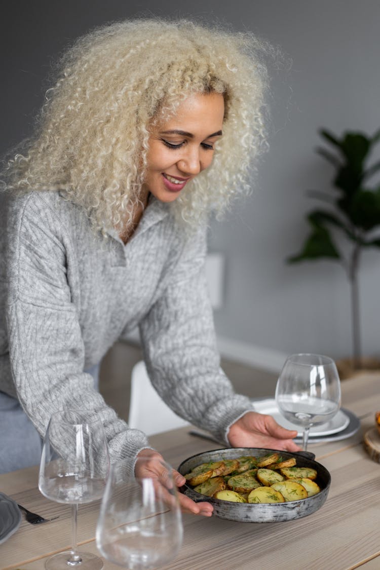 Cheerful Black Woman Putting Bowl Of Delicious Meal On Table