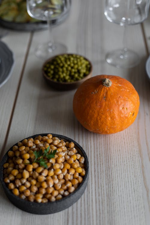 Free High angle of wooden table served with fresh beans and vegetables placed near empty crystal glasses for guests Stock Photo