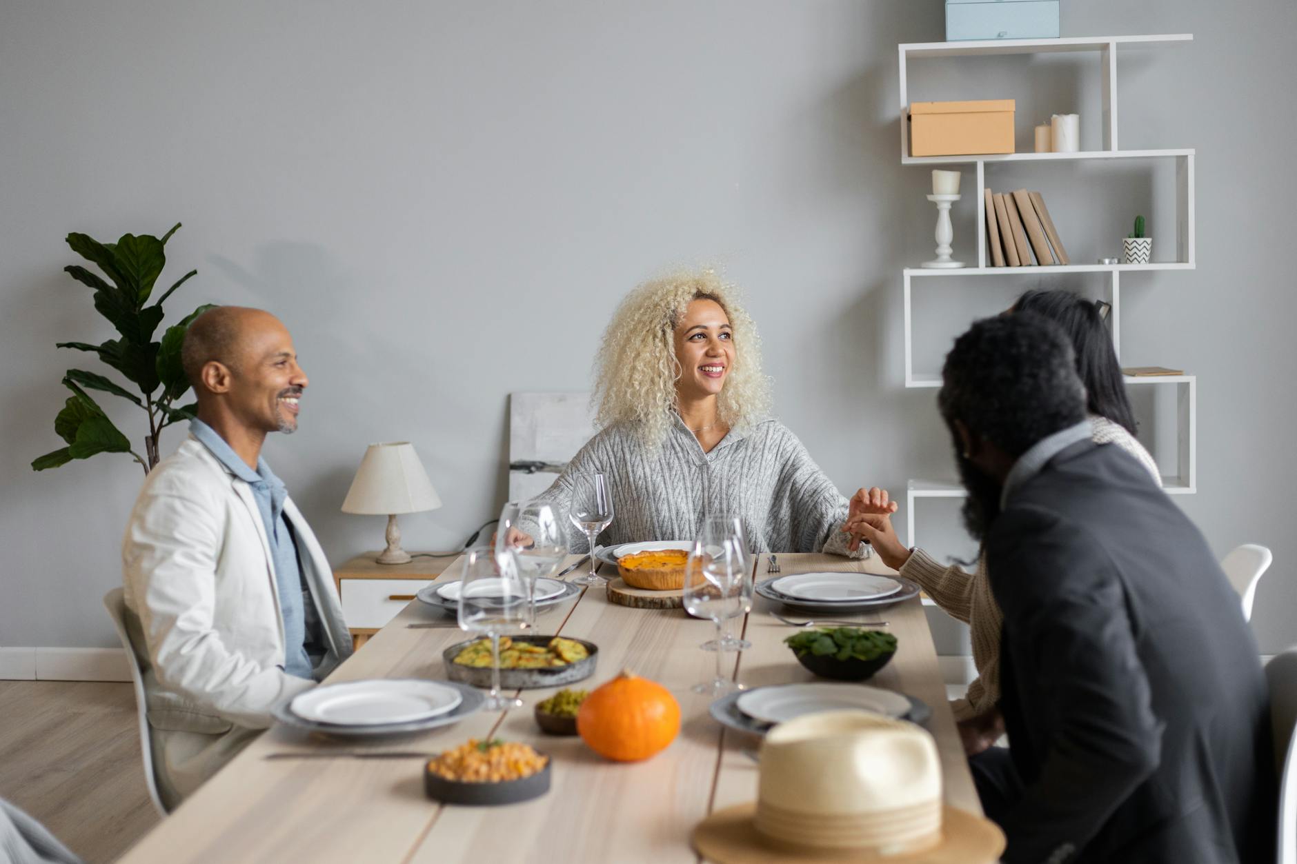 Happy multiracial people sitting at wooden table served with vegetarian food while having dinner together