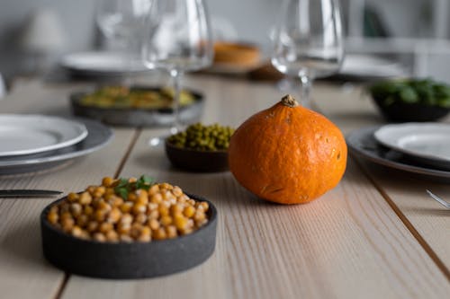Free High angle of wooden table served with delicious chickpeas and fresh ripe pumpkin near empty plates and glasses for guests Stock Photo